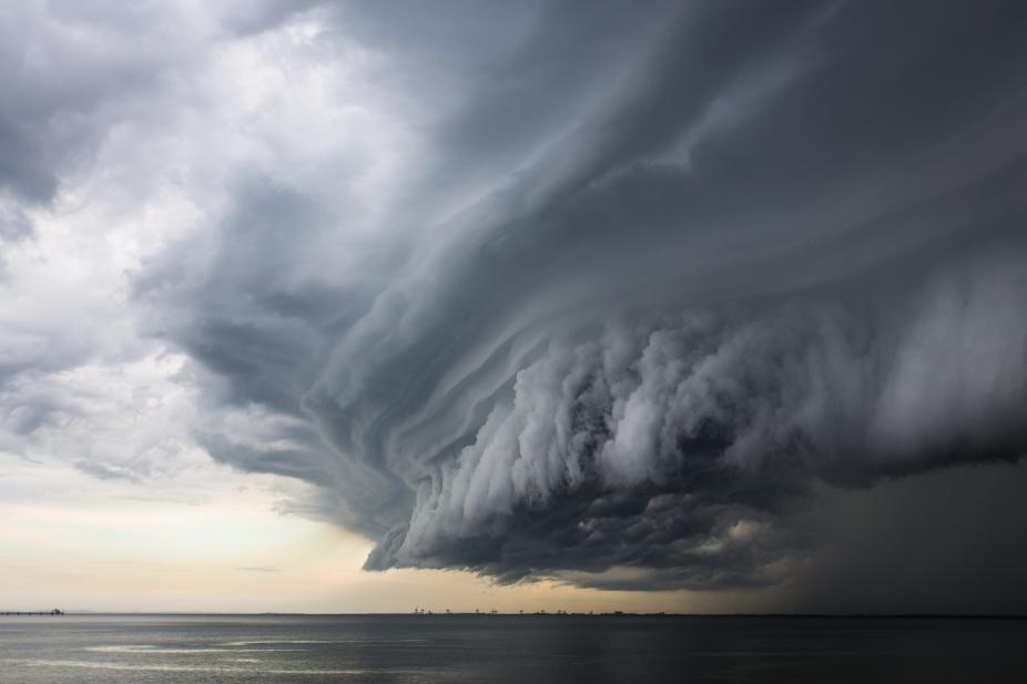 A mean looking huge storm cloud hovering over the ocean. iStock