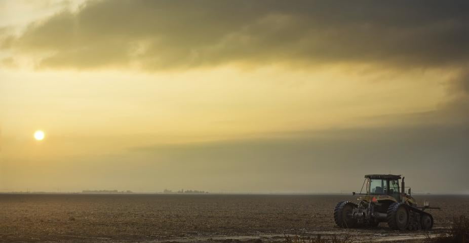 Silhouette of Tractor on Field at Foggy Dawn